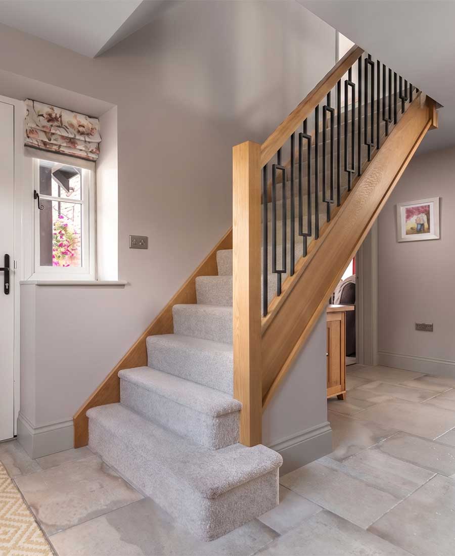 Craftsman's Oak staircase with carpet and black metal balusters by Stairplan