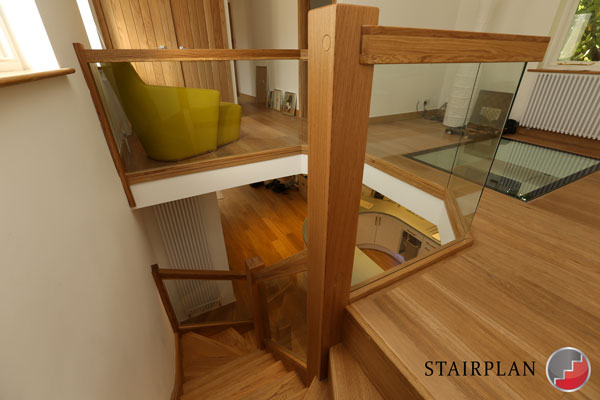 Stair landing balustrade panels of glass and oak handrail